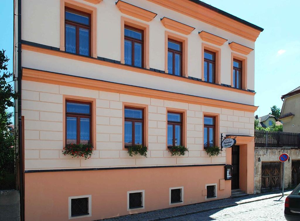 チェスキー・クルムロフにあるペンション ファルコの通りに面した窓のあるオレンジと白の建物