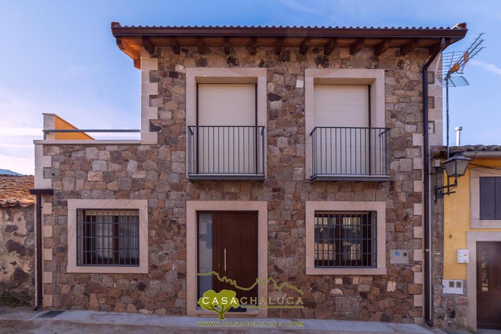 Cette maison en pierre dispose de fenêtres et d'un balcon. dans l'établissement Casa Chaluca, à La Aldehuela