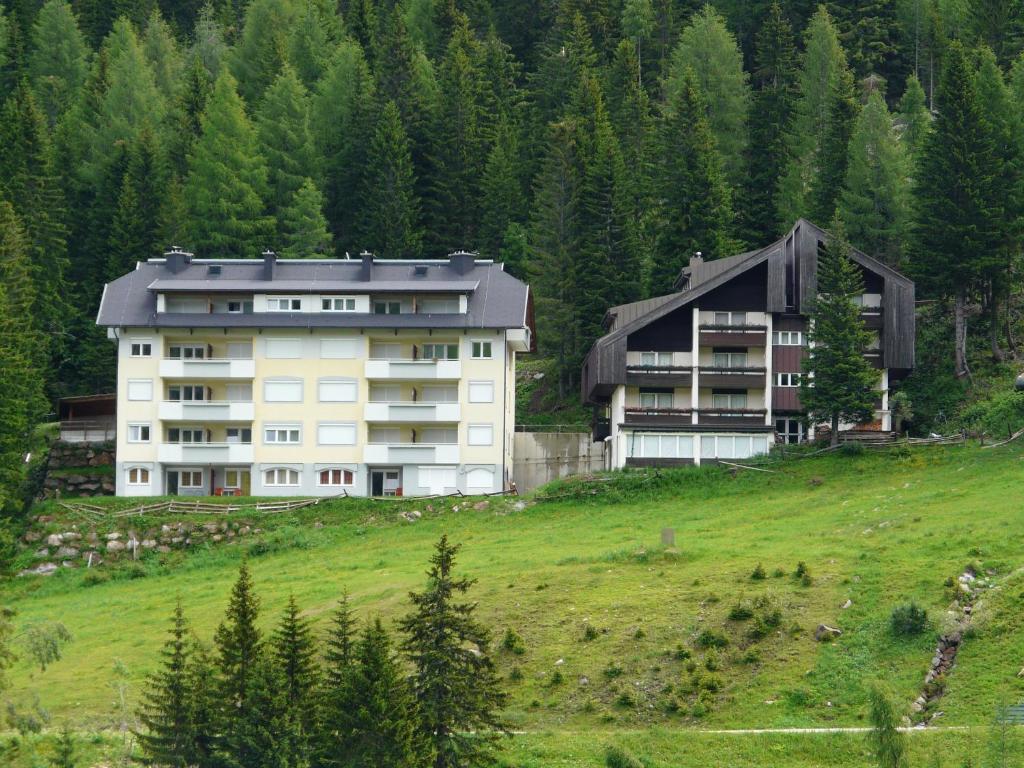 deux bâtiments sur une colline avec des arbres en arrière-plan dans l'établissement Appartementhaus CKPK Sonnenalpe Nassfeld, à Sonnenalpe Nassfeld