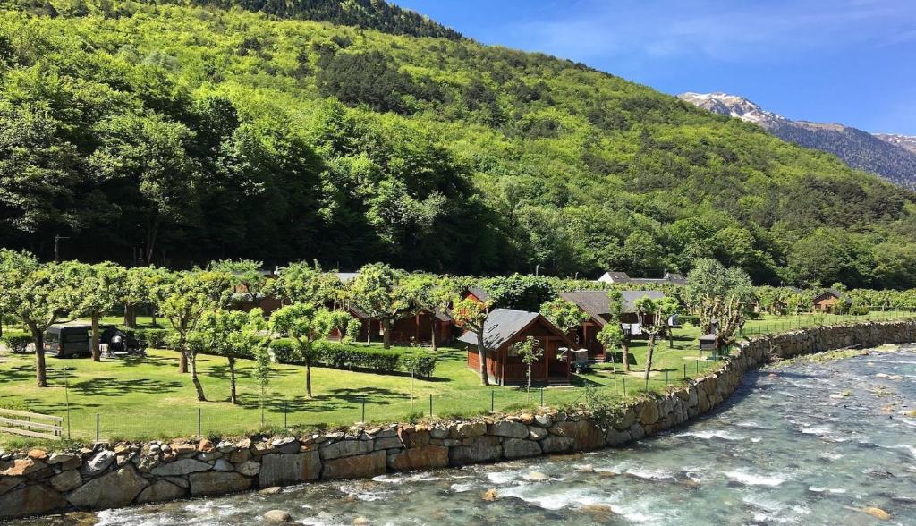 un complejo con una pared de piedra junto a un río en Bungalows Verneda Mountain Resort, en Arrós