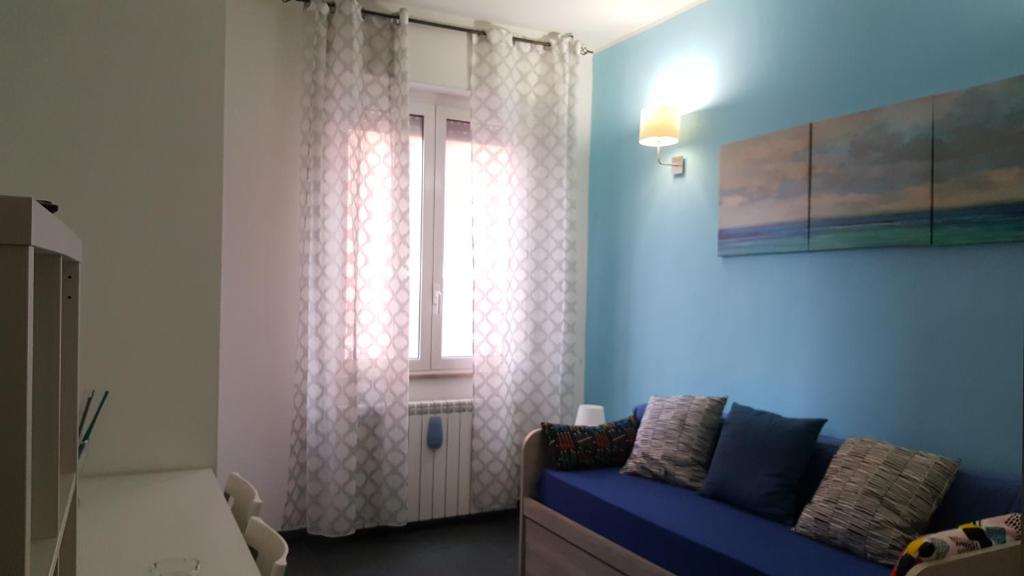 uma sala de estar com um sofá azul e uma janela em DaNicolas Cairoli Apartment em Monza