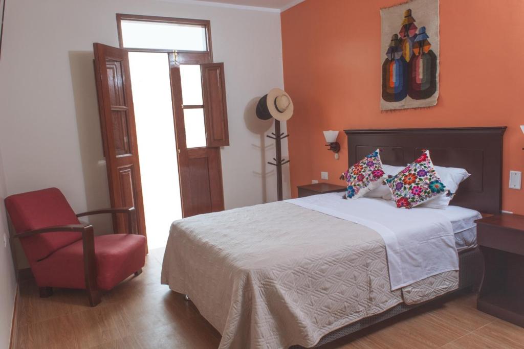 a bedroom with a bed and a red chair at Hospedaje Zaragoza in Ayacucho