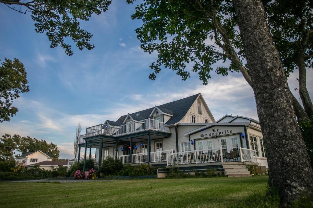 ein großes weißes Haus mit einer Veranda in der Unterkunft Auberge Seigneurie des Monts in Sainte-Anne-des-Monts