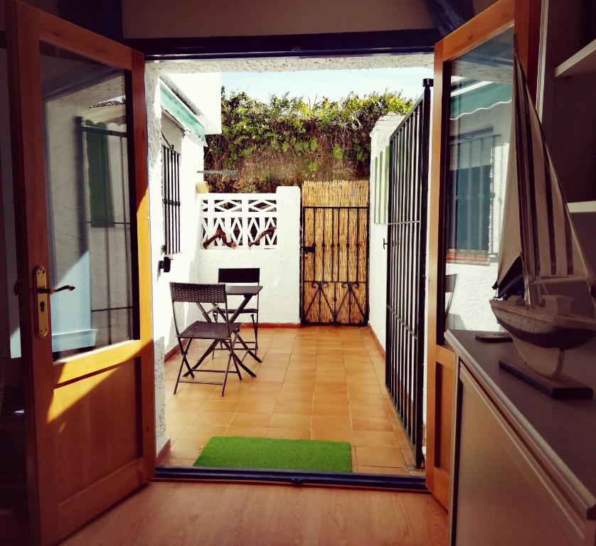 Une porte ouverte s'ouvre sur une terrasse avec une table et des chaises. dans l'établissement Apartamento La Muralla de Llanes, à Llanes
