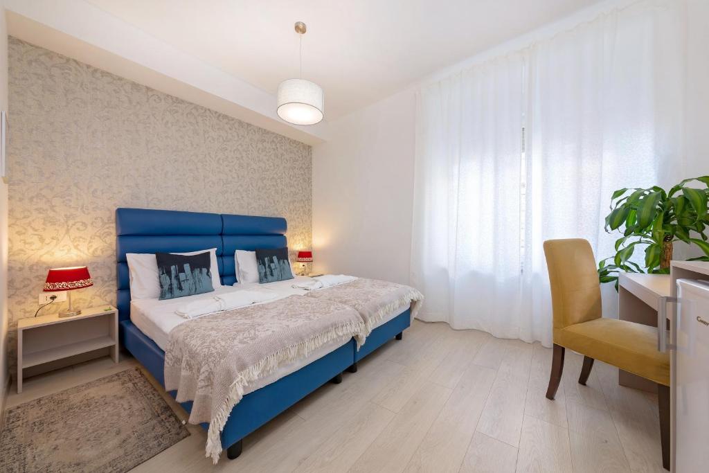 a bedroom with a blue bed and a chair at S. Martino Rooms in Pula