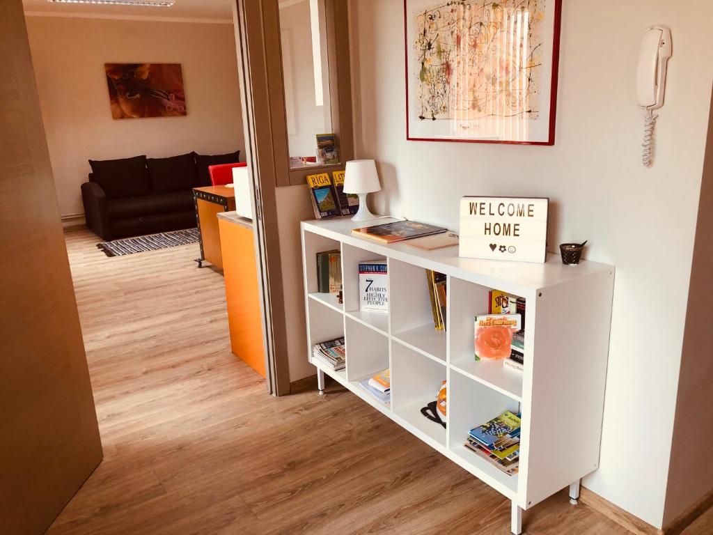 a white book shelf with a welcome home sign on it at Family or Group Apartment in Silent Center in Riga