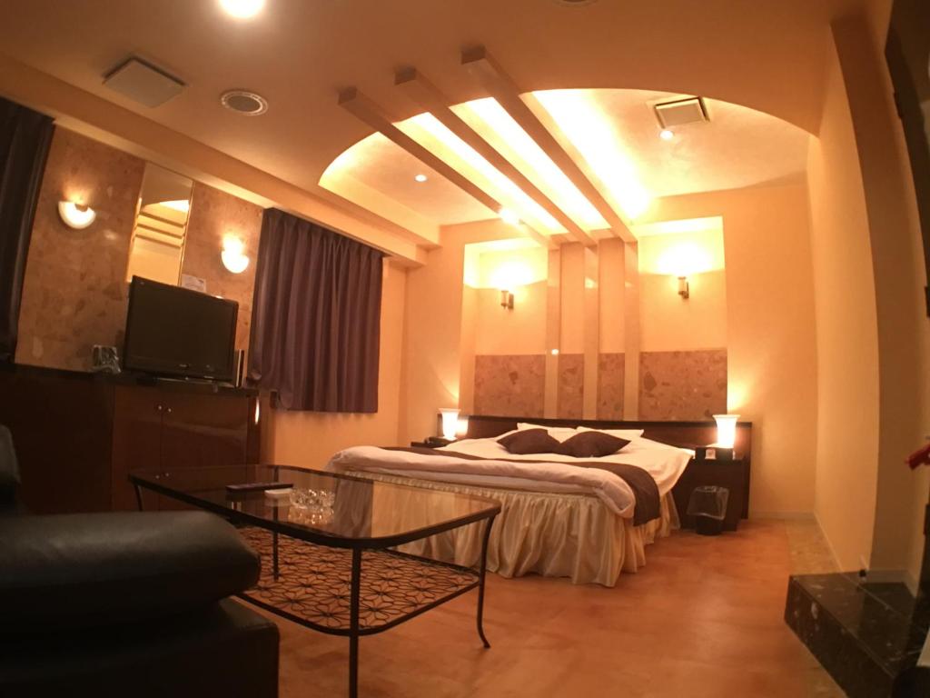 ein Hotelzimmer mit einem Bett und einem Tisch in der Unterkunft Hotel Orchid (Adult only) in Kurashiki