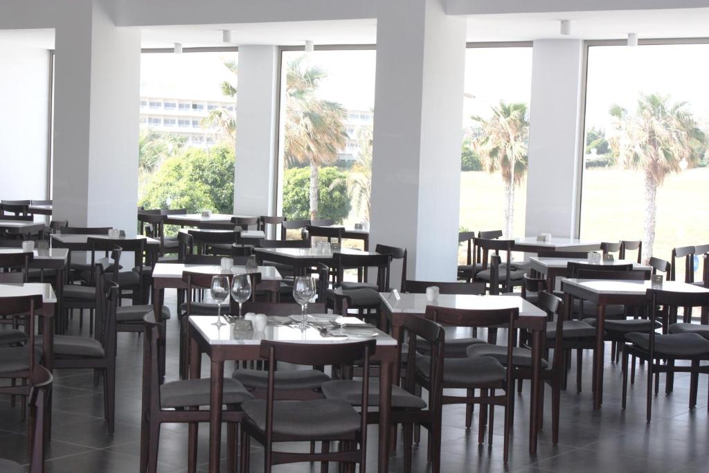 a dining room with tables and chairs and windows at Amphora Hotel & Suites in Paphos