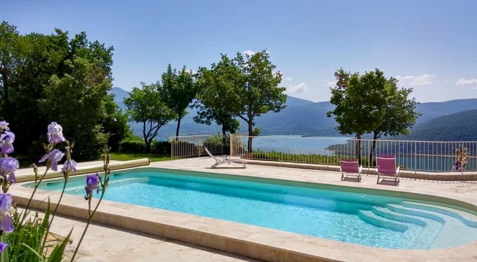 a pool with two chairs and a view of the water at Ferme Para Lou in Sainte-Croix-de-Verdon