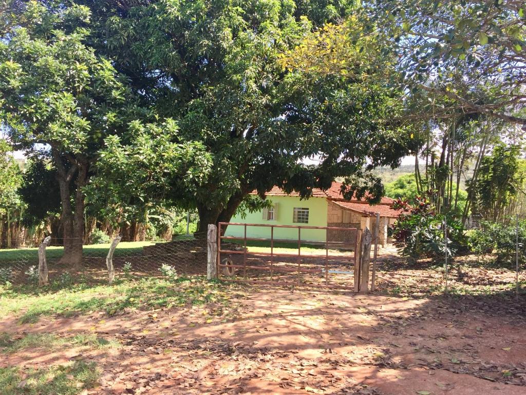 a fence in front of a house with a tree at Sítio Felicidade-Capitolio-Furnas-MG in Elisiário Lemos