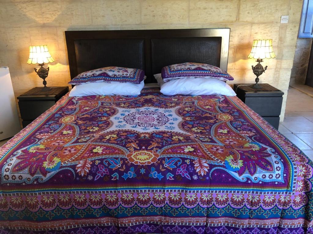 a bed with a colorful blanket and pillows on it at Ta Skorba Farmhouse Mgarr in Mġarr