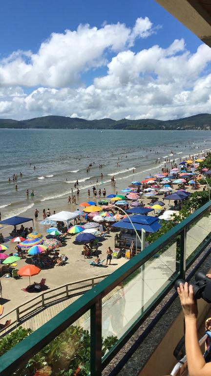 een strand met een stel mensen en parasols bij Apartamento a Beira Mar in Meia Praia