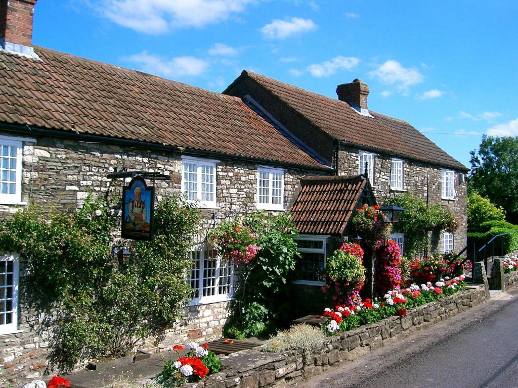 Pensford的住宿－The Carpenters Arms，一座古老的石头房子,前面有鲜花