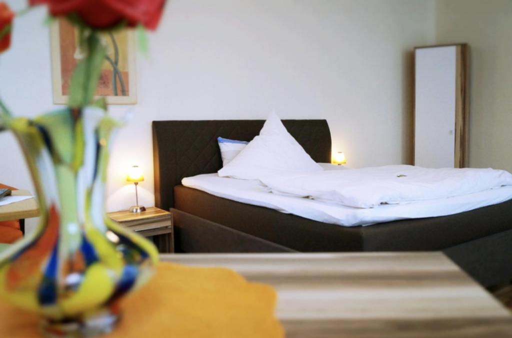 a bedroom with a bed and a vase with flowers on a table at Hotel-Cafe Maxx in Lengerich