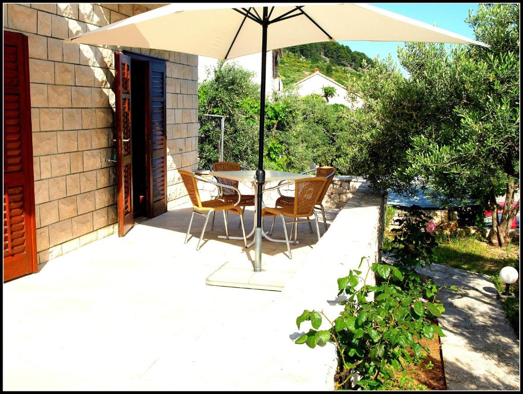 einen Tisch und Stühle unter einem Sonnenschirm auf einer Terrasse in der Unterkunft Apartments Pina in Bol