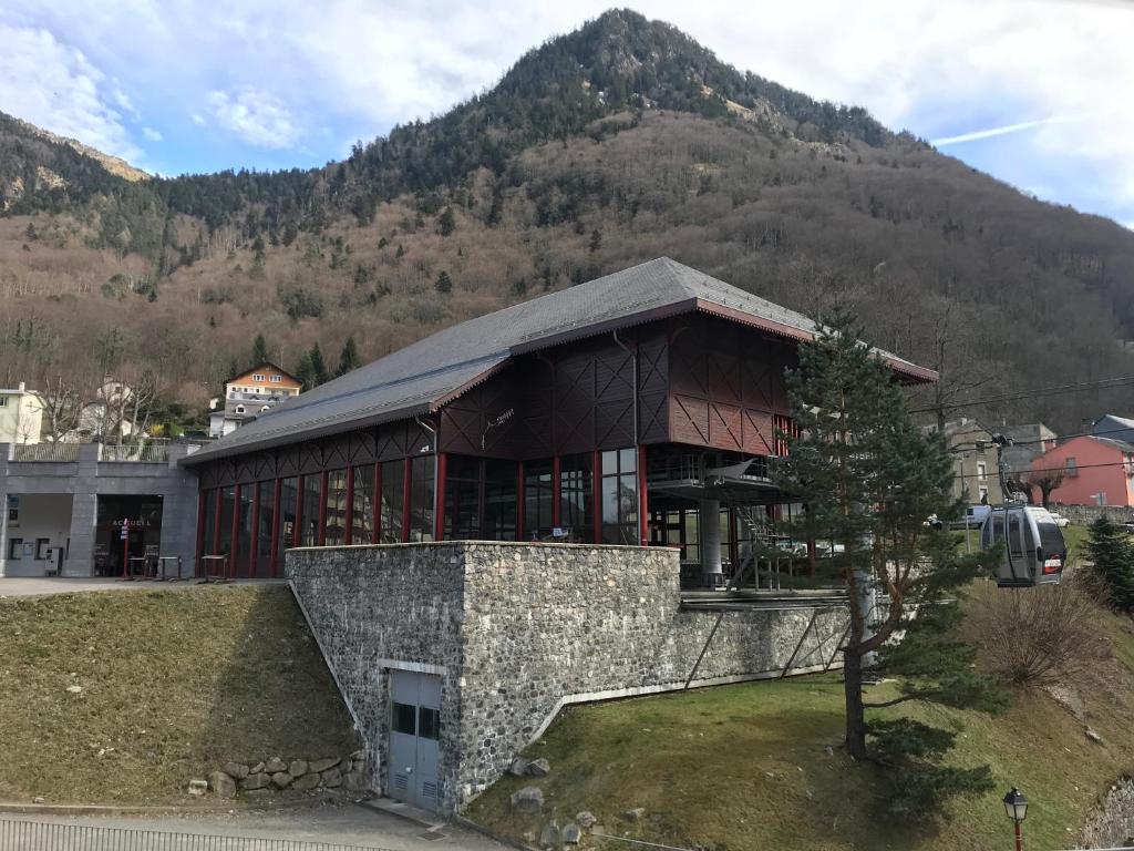 un grand bâtiment avec une montagne en arrière-plan dans l'établissement Pied télécabine avec parking couvert, T2 bis 5 personnes., à Cauterets