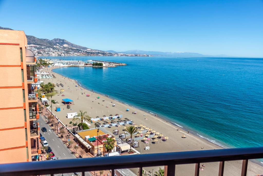 フエンヒロラにあるPerla 5, primera línea de playa y centricoのビーチの景色を望む客室で、パラソルが備わります。
