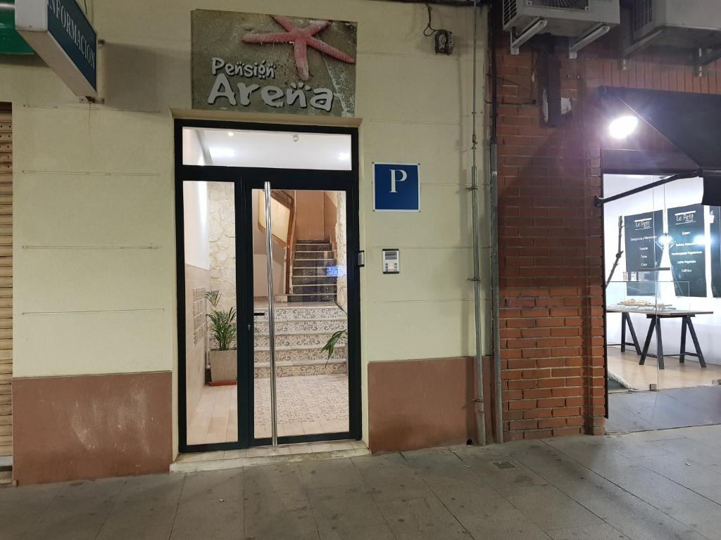 une porte menant à un restaurant avec un panneau sur un bâtiment dans l'établissement Pension Arena Alicante, à Alicante