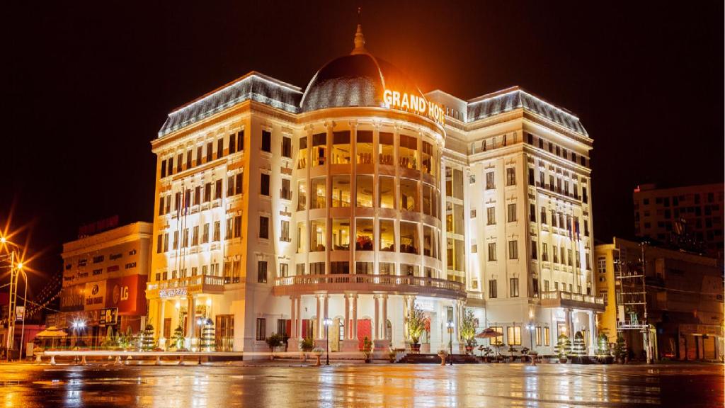 a large white building in a city at night at Grand Hotel in Hòa Bình