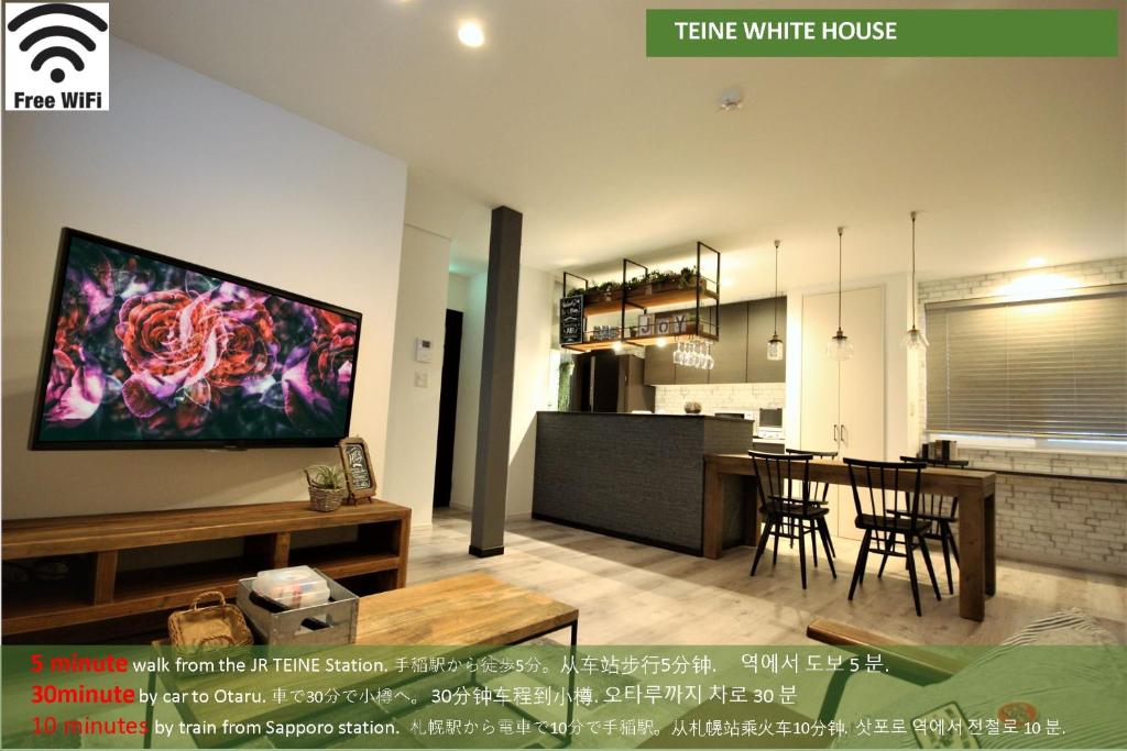 a living room and kitchen with a large screen tv at TEINE WHITE HOUSE in Sapporo