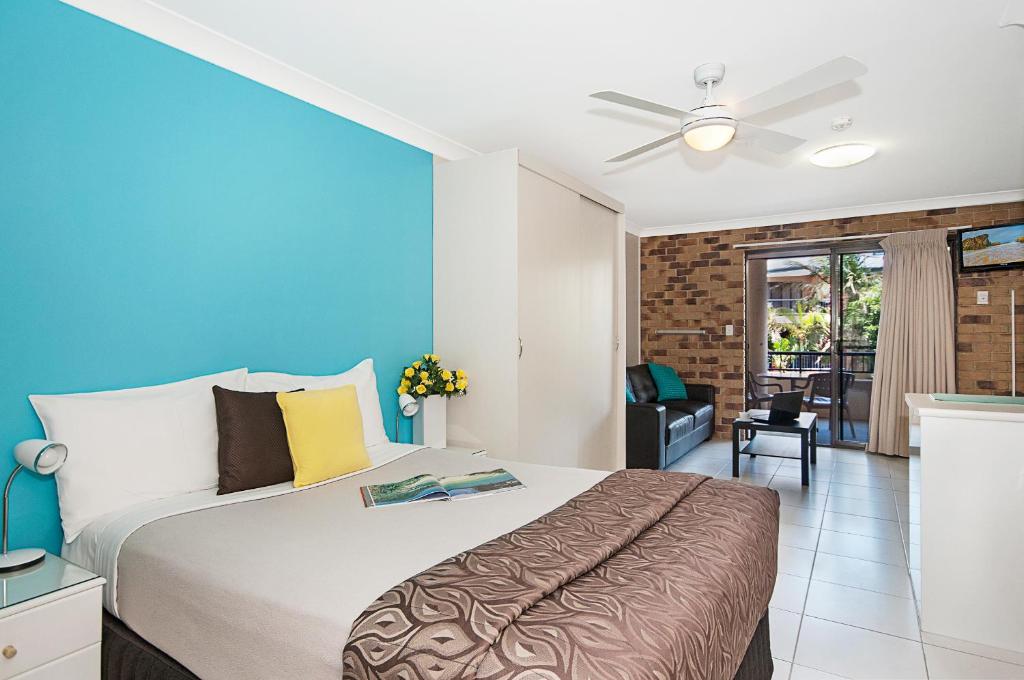 a bedroom with a large bed and a large window at Byron Bayside Central Studio Apartments in Byron Bay