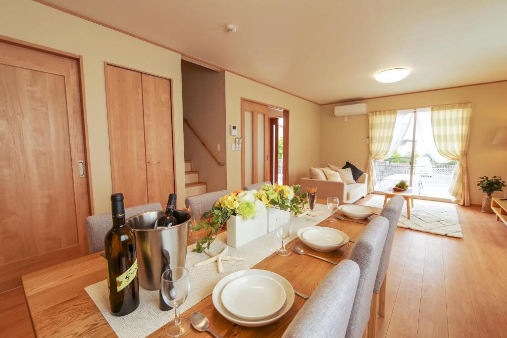 a dining room with a table with a bottle of wine at Hyakuna Terrace in Nanjo