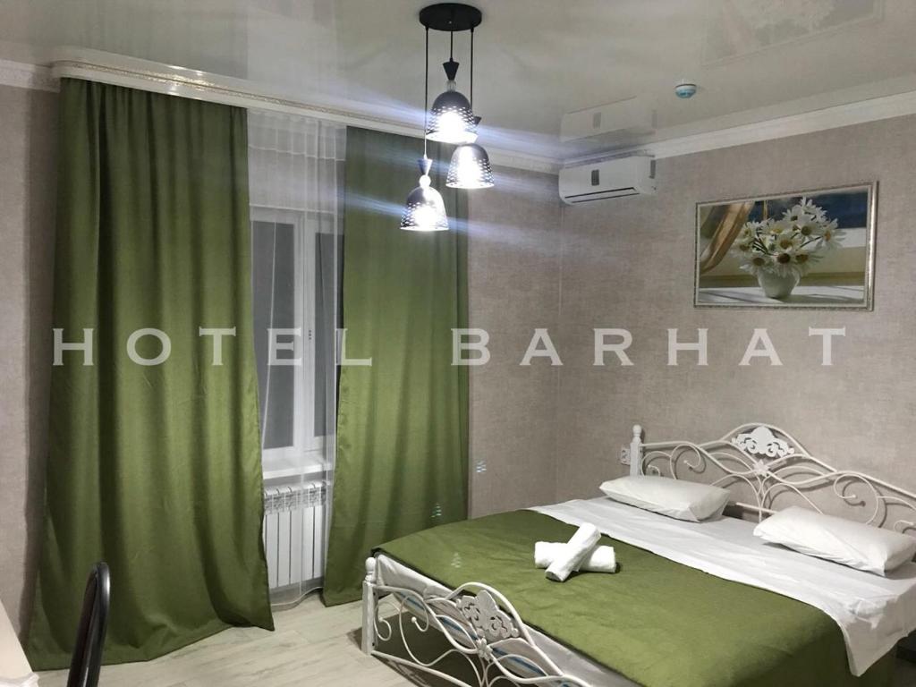 1 dormitorio con 1 cama y cortina verde en Hotel Barhat Аktobe en Aktobe