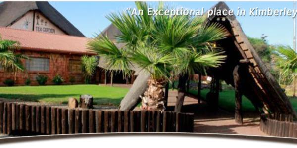 a slide in front of a house with palm trees at Kalahari Lodge Kimberley in Kimberley