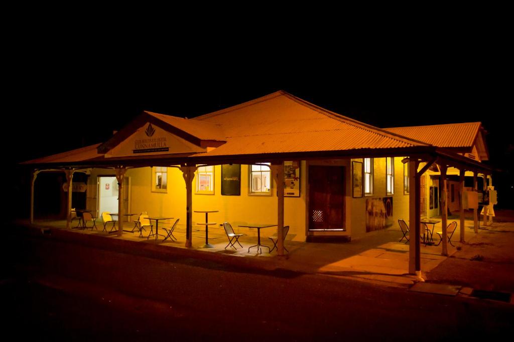 un edificio amarillo con mesas y sillas al aire libre por la noche en Club Boutique Hotel Cunnamulla, en Cunnamulla