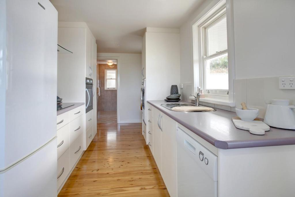 a white kitchen with a sink and a window at Little Hacienda - Port Lincoln in Port Lincoln