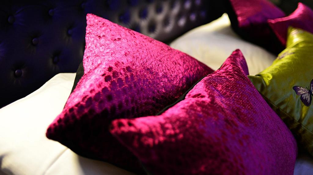 a group of pink pillows sitting on a bed at Hotel No13 in Bergen