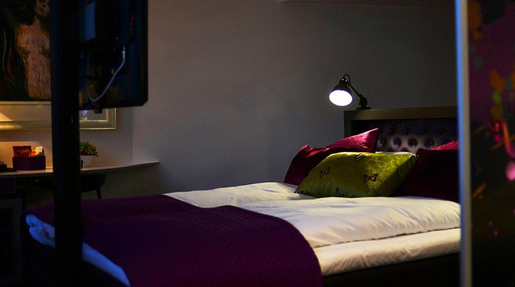 a bedroom with a bed with colorful pillows on it at Hotel No13 in Bergen