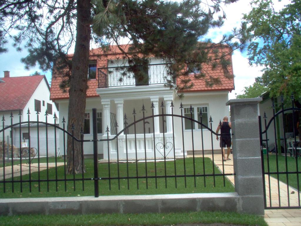 a woman walking past a fence in front of a house at Rebeka Villa in Zamárdi