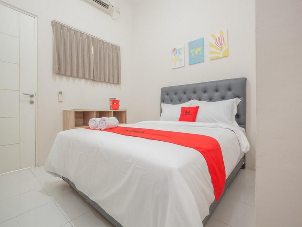 ein Schlafzimmer mit einem großen Bett mit einer roten und weißen Decke in der Unterkunft RedDoorz near Ciputra Golf Surabaya in Surabaya