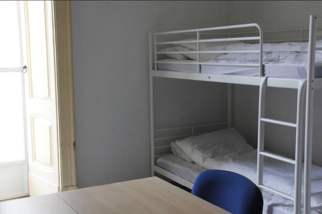 Cette chambre comprend 2 lits superposés et une chaise bleue. dans l'établissement Basic 8 Bed Mixed Dorm (share Bathroom), à Naples