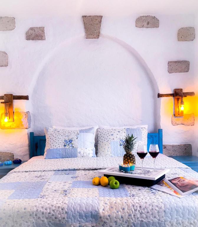 a bed with a tray of fruit and two glasses of wine at Monat Otel Alaçatı in Alaçatı