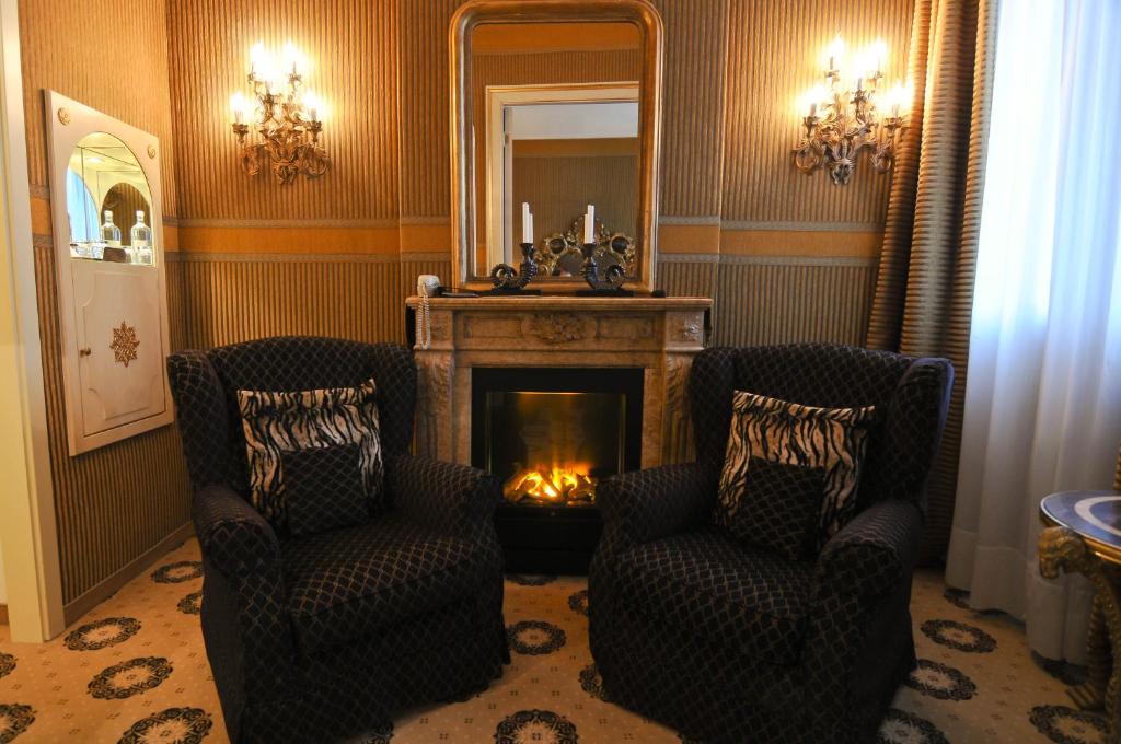 a living room with two chairs and a fireplace at Hotel Metropole Venezia in Venice