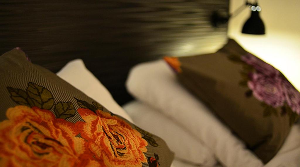 a bed with a pillow with flowers on it at Hotel No13 in Bergen