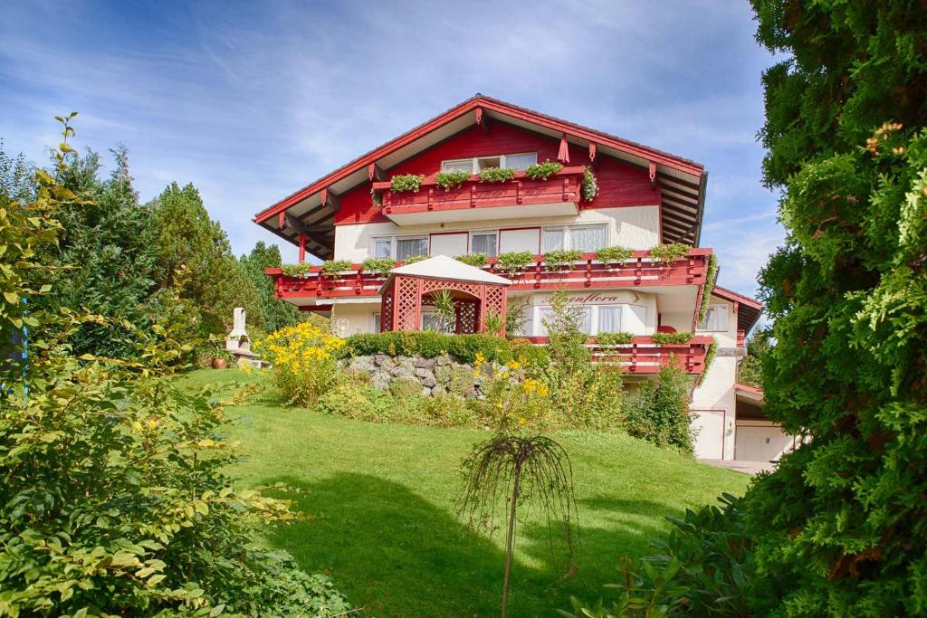 una casa en una colina con un patio verde en Alpenflora Ferienwohnungen en Ofterschwang
