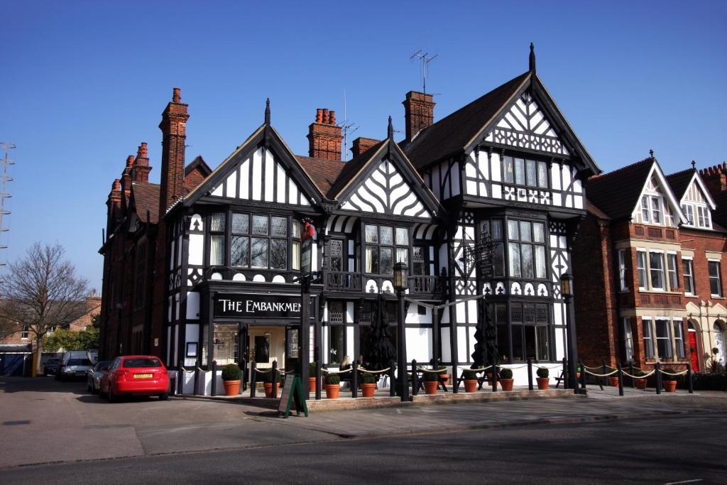 a black and white building with a red car in front at Embankment Hotel in Bedford