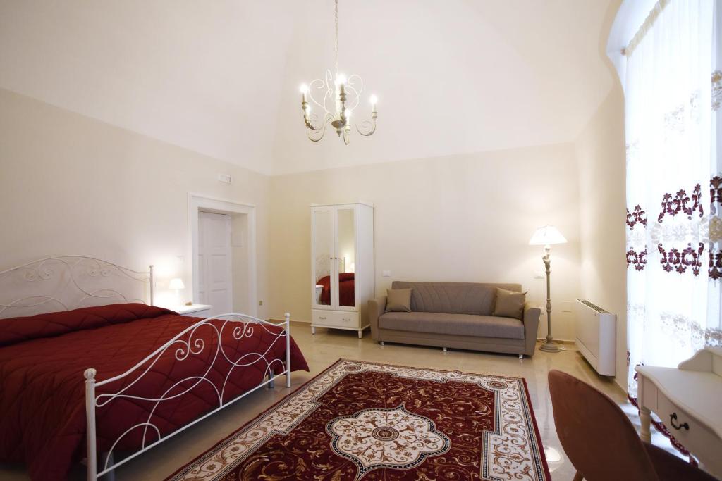 a bedroom with a bed and a couch and a chandelier at KAPSOTT B&B in Bisceglie
