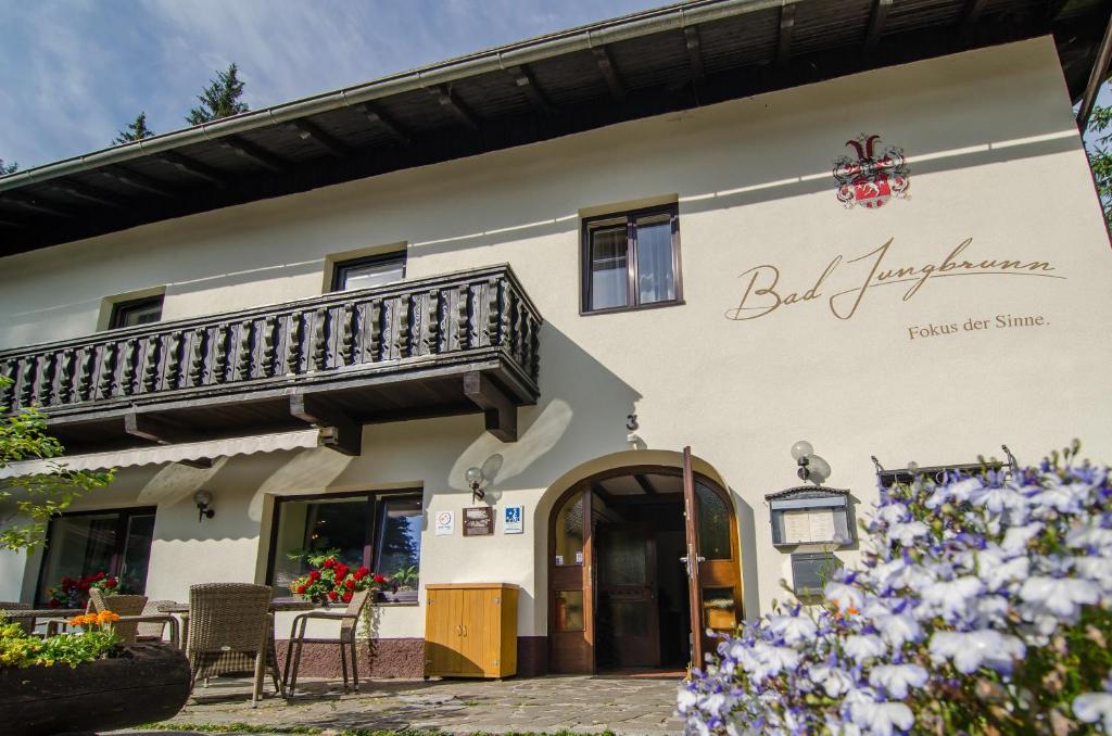 un edificio con balcón, mesa y sillas en Waldhotel Bad Jungbrunn, en Tristach