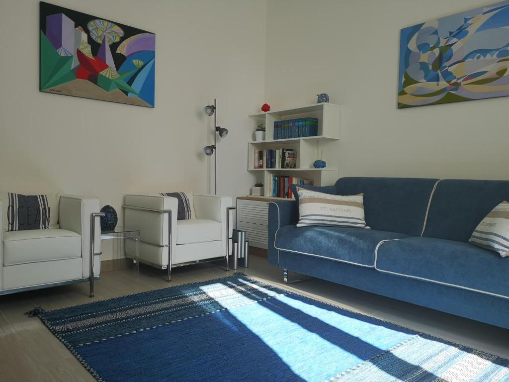 een woonkamer met een blauwe bank en 2 witte stoelen bij Vittoria home 44 in Terracina