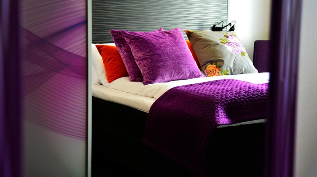 a bed with purple and orange pillows on it at Hotel No13 in Bergen