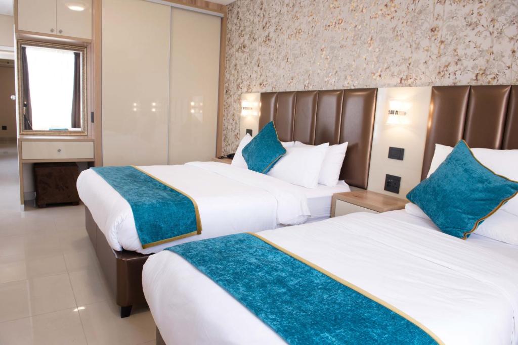 2 Betten in einem Hotelzimmer mit blauen Kissen in der Unterkunft Britannia Hotel in Durban
