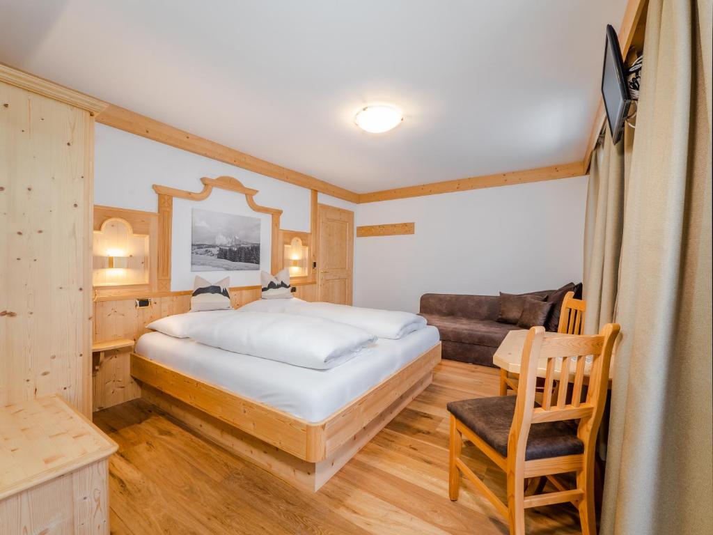 a bedroom with a large bed and a couch at B&B MARINA contacless check in in Santa Cristina in Val Gardena