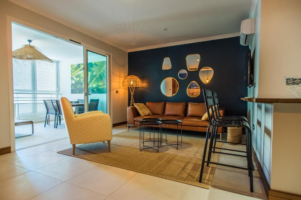 a living room with a couch and a table and chairs at L'Appart du Tropiclub - bien-être à 2 pas du lagon in Filaos