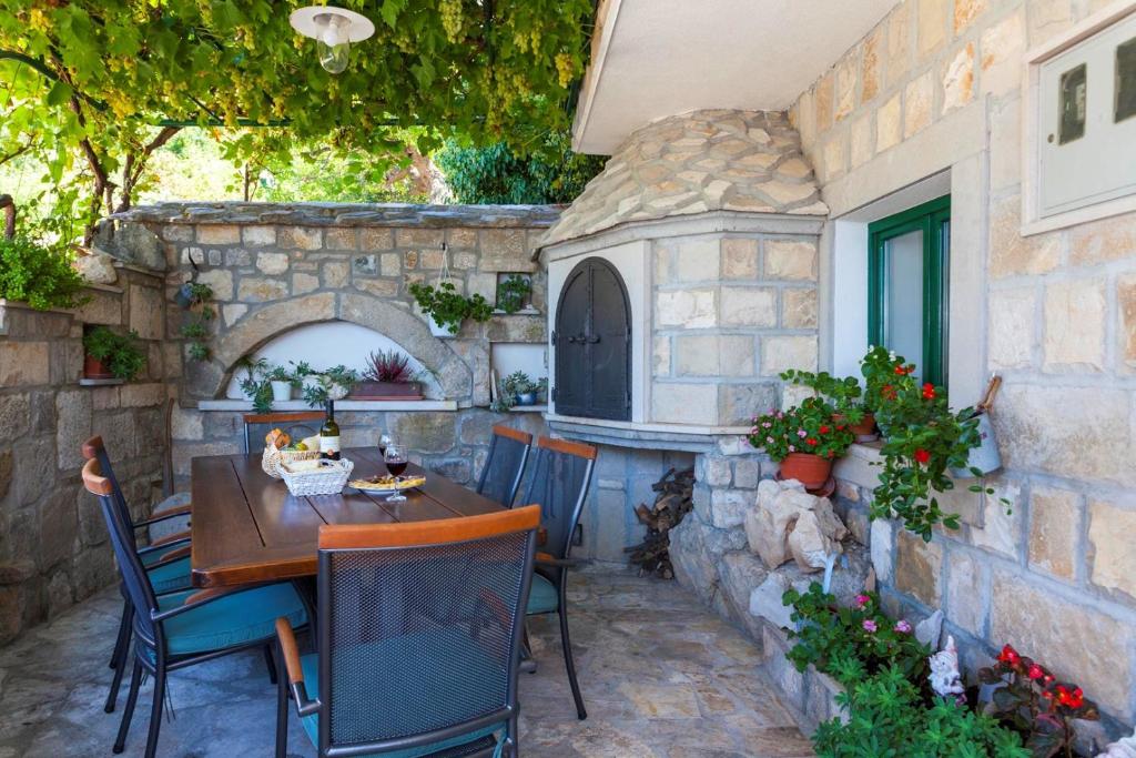 d'une terrasse avec une table, des chaises et un four en pierre. dans l'établissement Holiday house Layla in Tucepi, sea view, à Tučepi