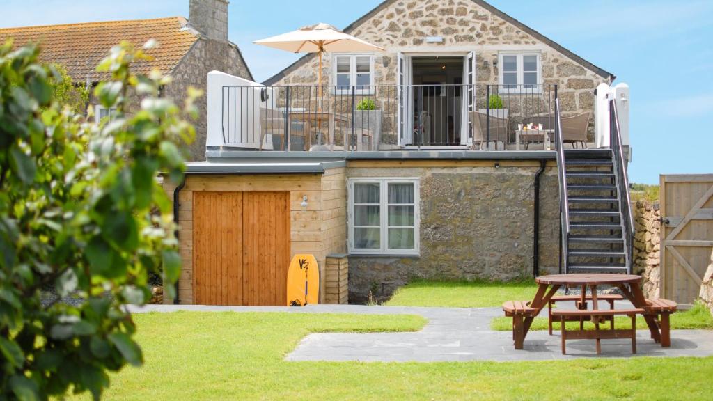 a house with a patio and a table and an umbrella at Saddle and Stable Rooms in Sennen