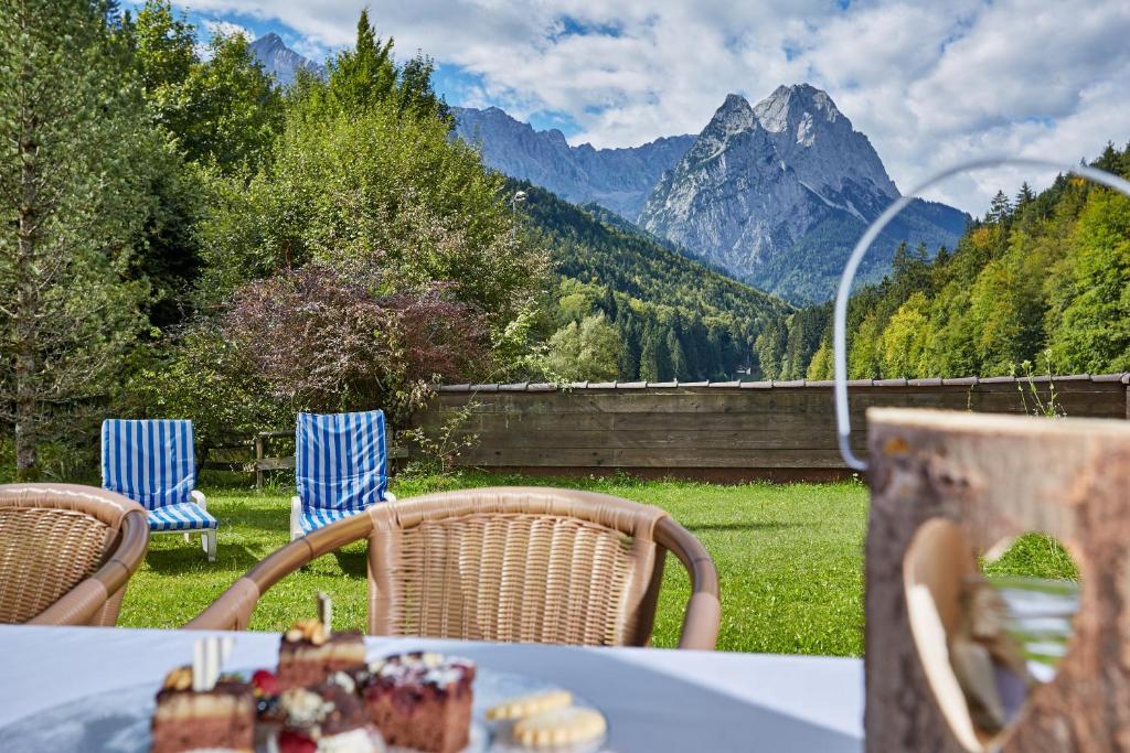 a table and chairs with a view of a mountain at Ferienwohnungen - Seehaus Riessersee in Garmisch-Partenkirchen